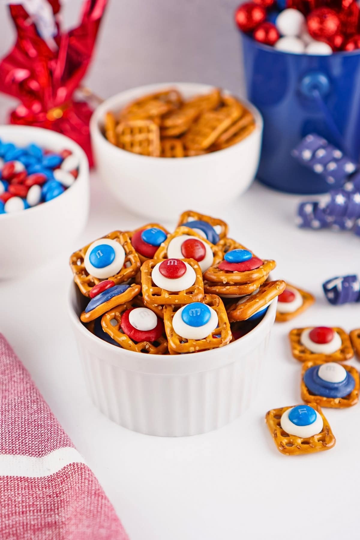 Square pretzels topped with red, white, and blue candies in a small white bowl.