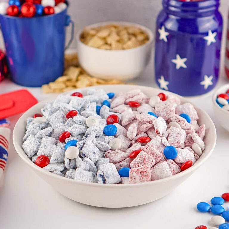 A bowl of red, white, and blue patriotic snack mix sits on a table.