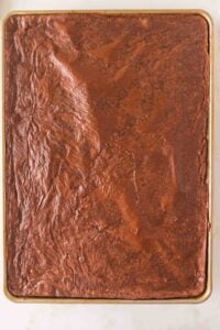 A sheet pan filled with a large, uncut layer of chocolate brownies.