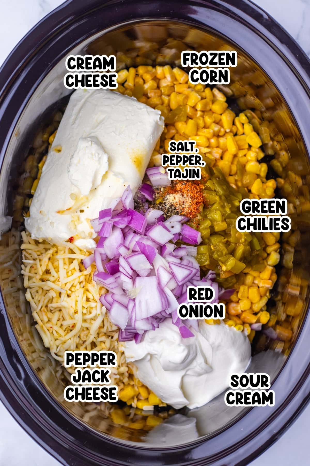 Crockpot filled with corn, cheeses, green chilies, red onion, and seasonings.