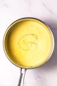 A saucepan with creamy yellow sauce and a swirl of vanilla on top.