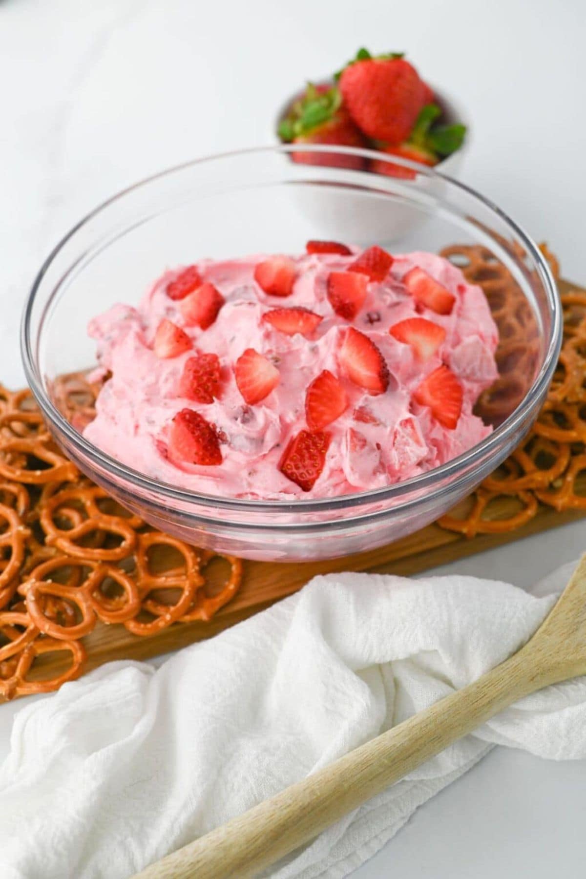 A bowl of pink strawberry salad&mdash;an easy strawberry recipe&mdash;served with pretzels.