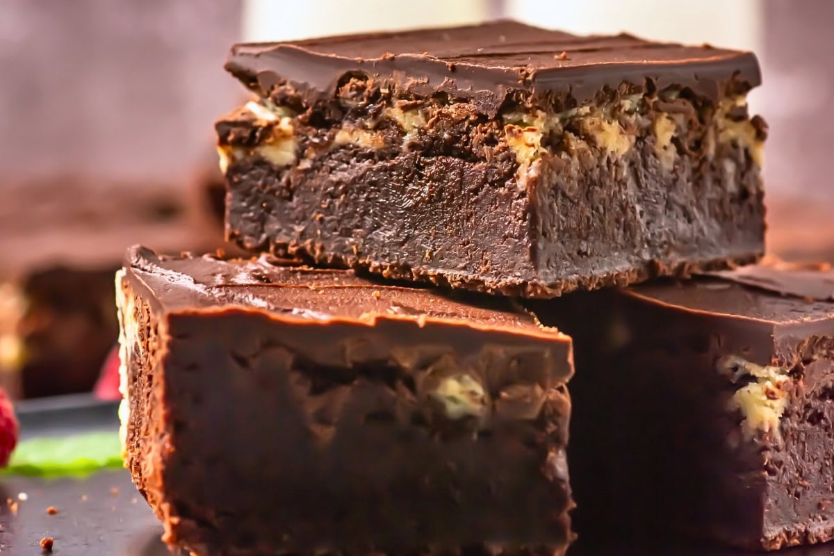 Close-up of thick, fudgy chocolate brownies stacked on top of each other.