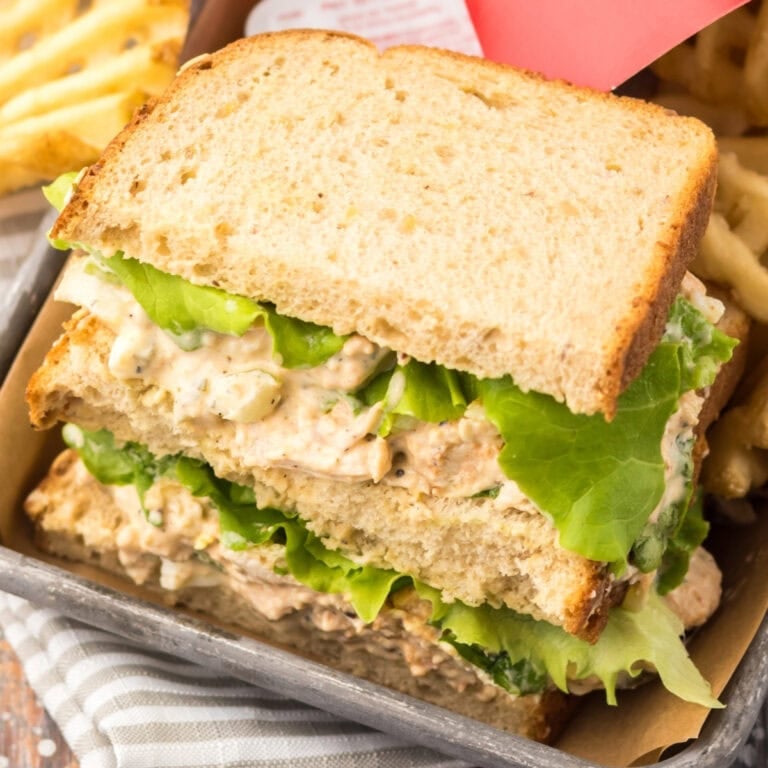 Chicken salad sandwich with lettuce on wheat bread, served with waffle fries.