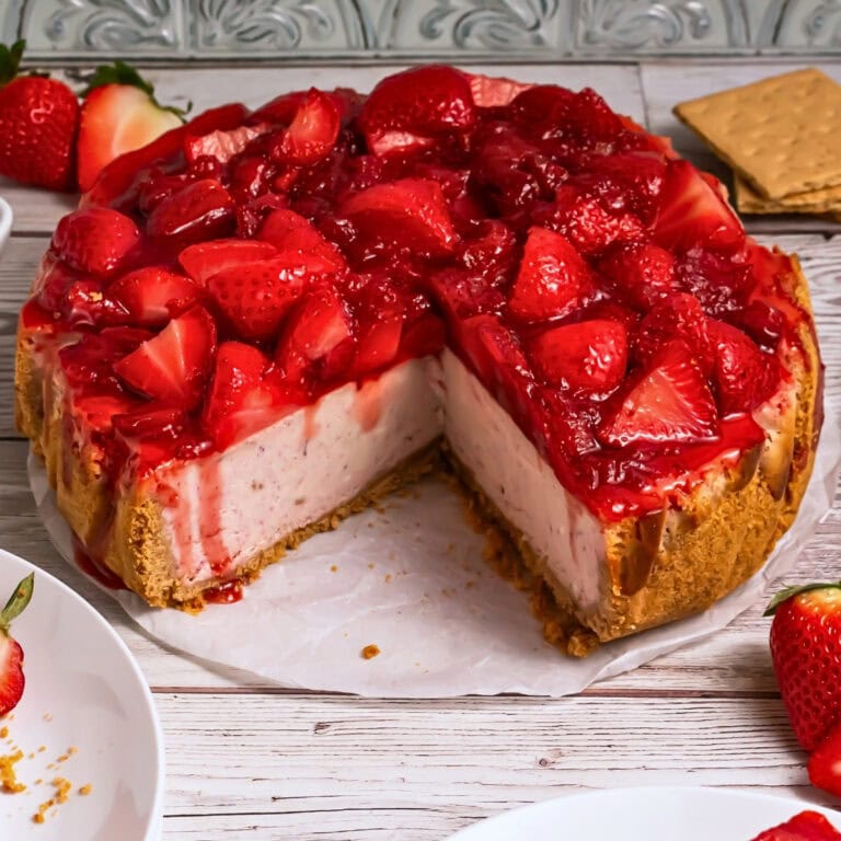 A strawberry cheesecake with a graham cracker crust and fresh strawberry topping.