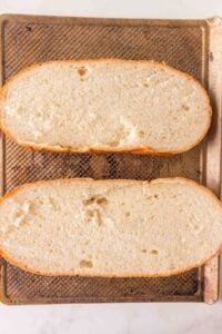 Two halves of a sliced loaf of bread on a textured baking sheet.