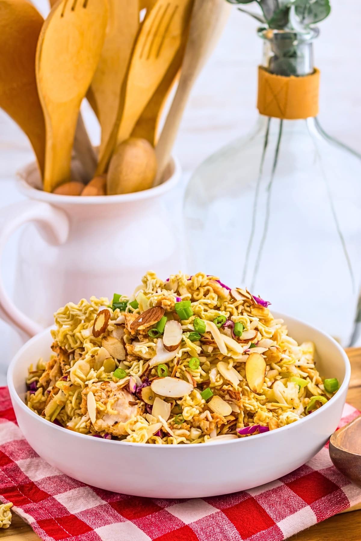 Ramen noodle salad with almonds and scallions in a white bowl.