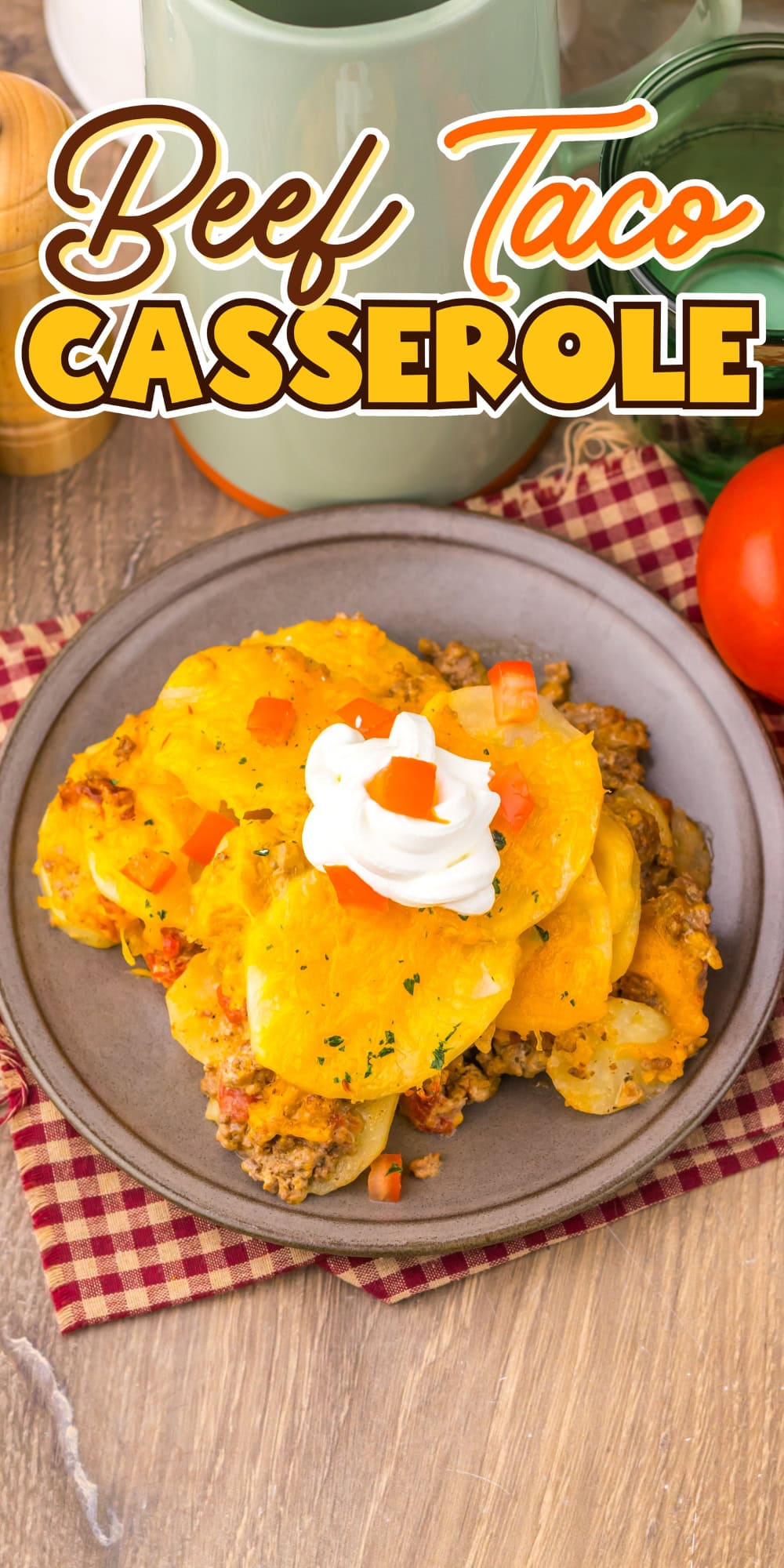 A plate of beef taco casserole topped with sour cream and diced tomatoes.
