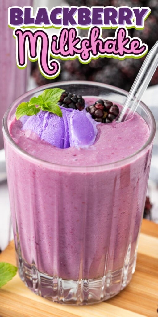 A glass of blackberry milkshake topped with blackberries, mint, and purple ice cream.