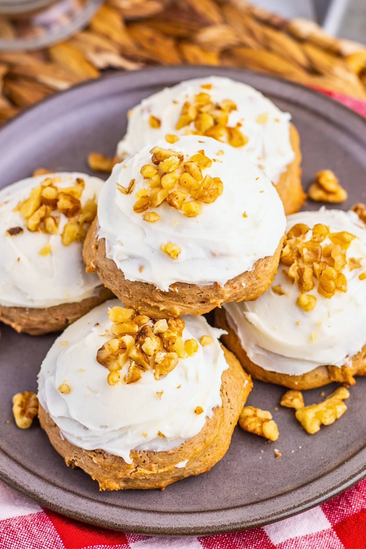 Five frosted cookies topped with chopped walnuts on a gray plate.