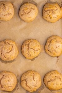 Nine round biscuits on a parchment-lined baking sheet, evenly spaced in rows.