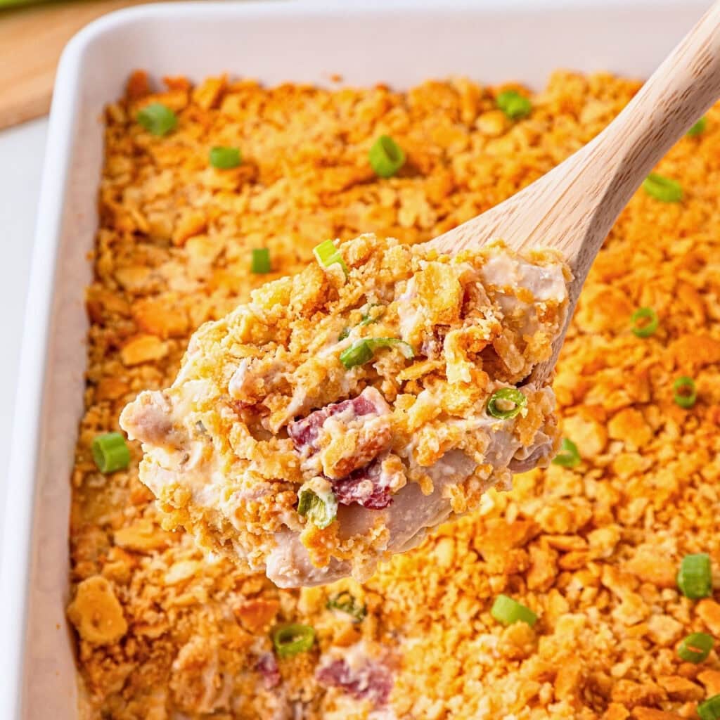 A spoonful of creamy casserole topped with crushed crackers and green onions.