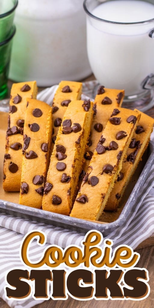 A tray of chocolate chip cookie sticks with glasses of milk in the background.