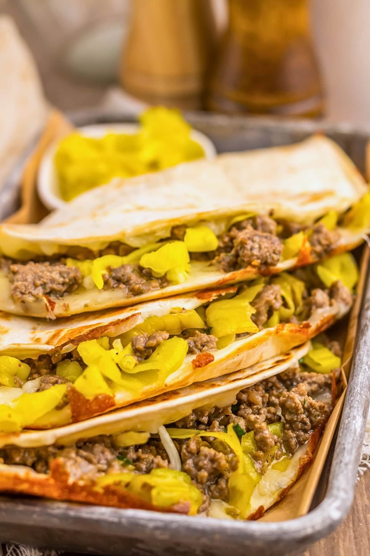 Three tacos filled with ground beef and yellow peppers on a tray.