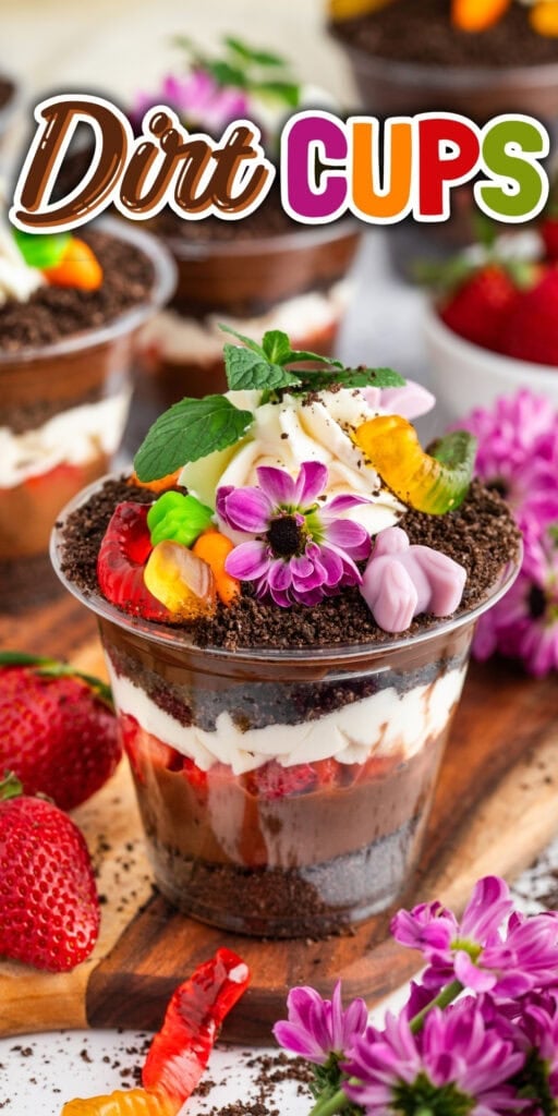 A chocolate dirt cup dessert topped with gummy worms and colorful flowers.
