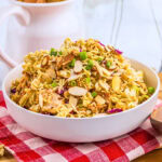 Asian ramen noodle salad with chicken and almonds in a white bowl.