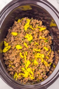 Seasoned ground beef with sliced yellow peppers in a slow cooker.