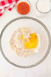 Large bowl with flour, shredded hashbrowns, eggs; milk and salsa beside it.