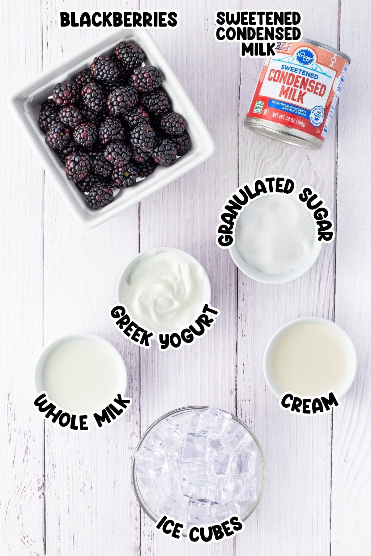 Top view of labeled ingredients for a blackberry milkshake on a white surface.