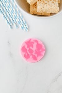 Pink silicone mold with mermaid tail shapes on a white surface.
