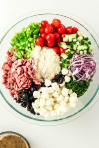 A bowl of chopped salad ingredients, including cheese, veggies, and salami.