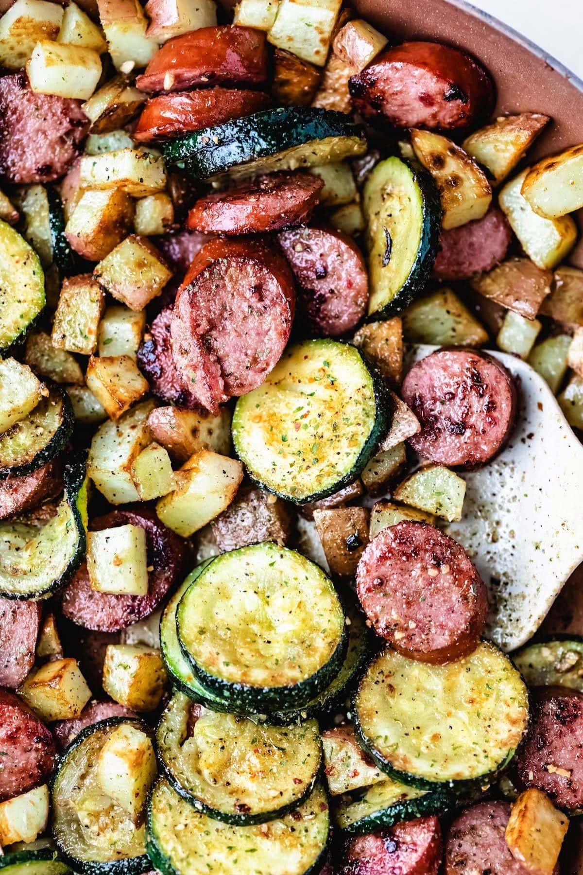 Saut&eacute;ed kielbasa sausage meals with zucchini and diced potatoes in a skillet.