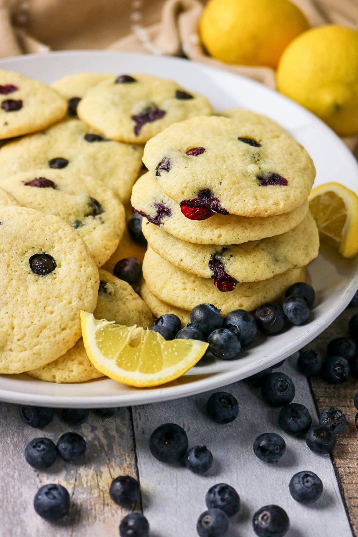 A plate of blueberry cookies with lemon slices and fresh blueberries.