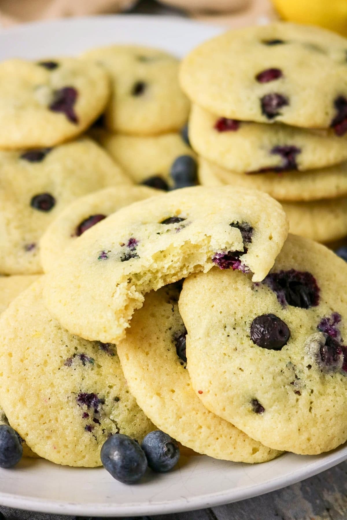 A plate of blueberry cookies, with one cookie partially eaten on top.