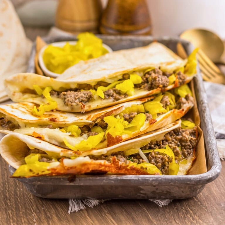 Four tacos filled with ground beef and pickles in a baking tray.
