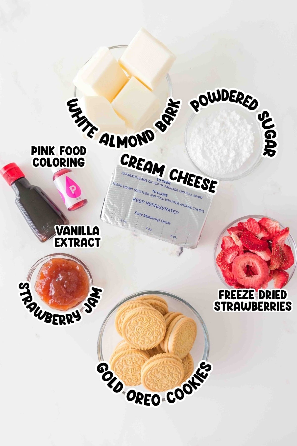 Ingredients for strawberry cheesecake truffles labeled in bowls on a white surface.