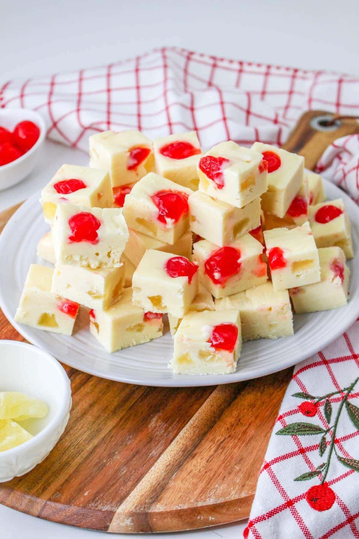 A plate of white fudge squares with red cherries, perfect for pineapple recipes.