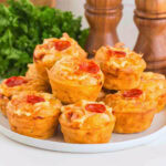 A plate of mini pizza muffins topped with cheese and pepperoni slices.