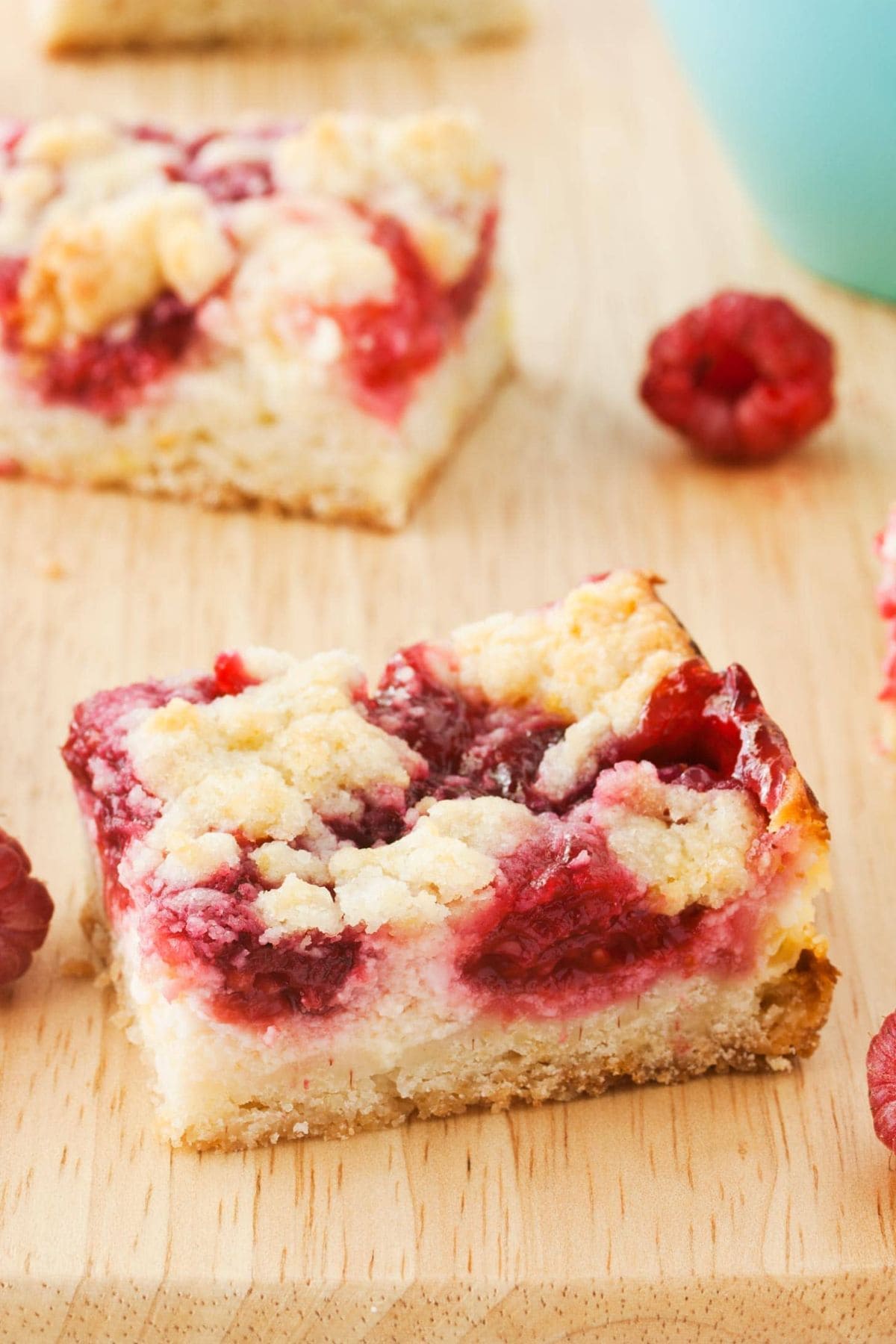 A raspberry crumb bar sits on a board—perfect for easy raspberry recipes.