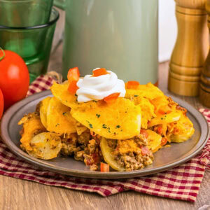 A plate of cheesy nachos topped with sour cream and diced tomatoes.