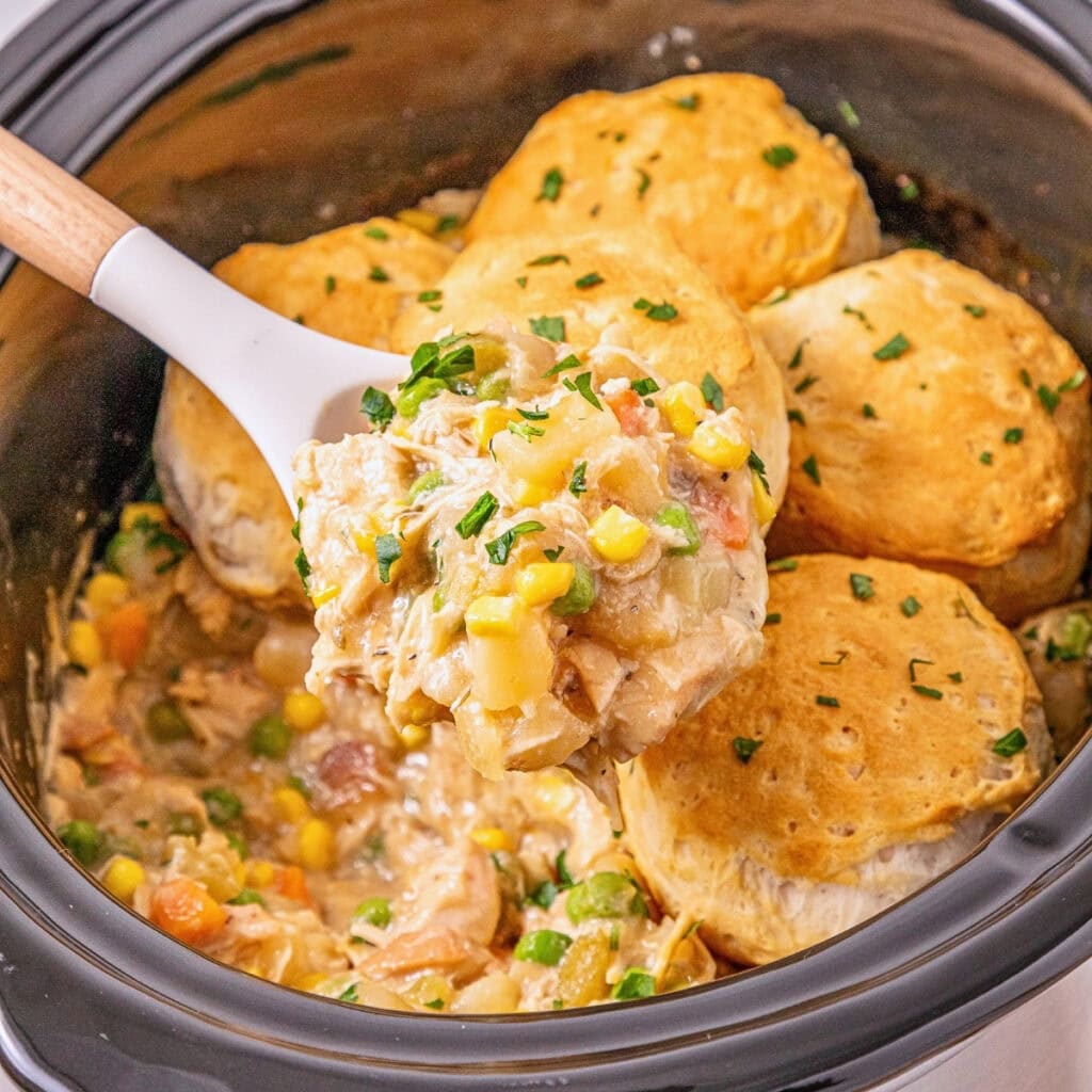 Slow cooker chicken pot pie with biscuits, vegetables, and creamy sauce.