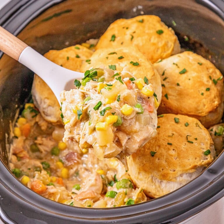 Slow cooker chicken pot pie with biscuits, vegetables, and creamy sauce.
