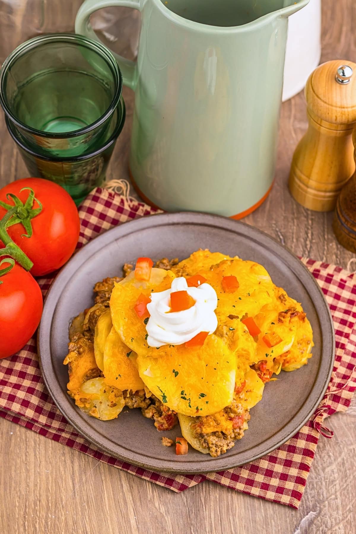 A plate of cheesy baked potatoes topped with sour cream and diced tomatoes.