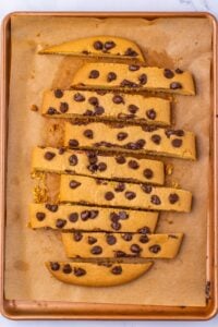Sliced chocolate chip biscotti on a parchment-lined baking sheet.