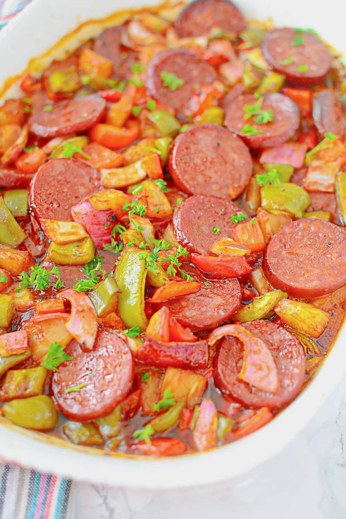 Kielbasa sausage meals with bell peppers and onions, baked and herb-garnished.