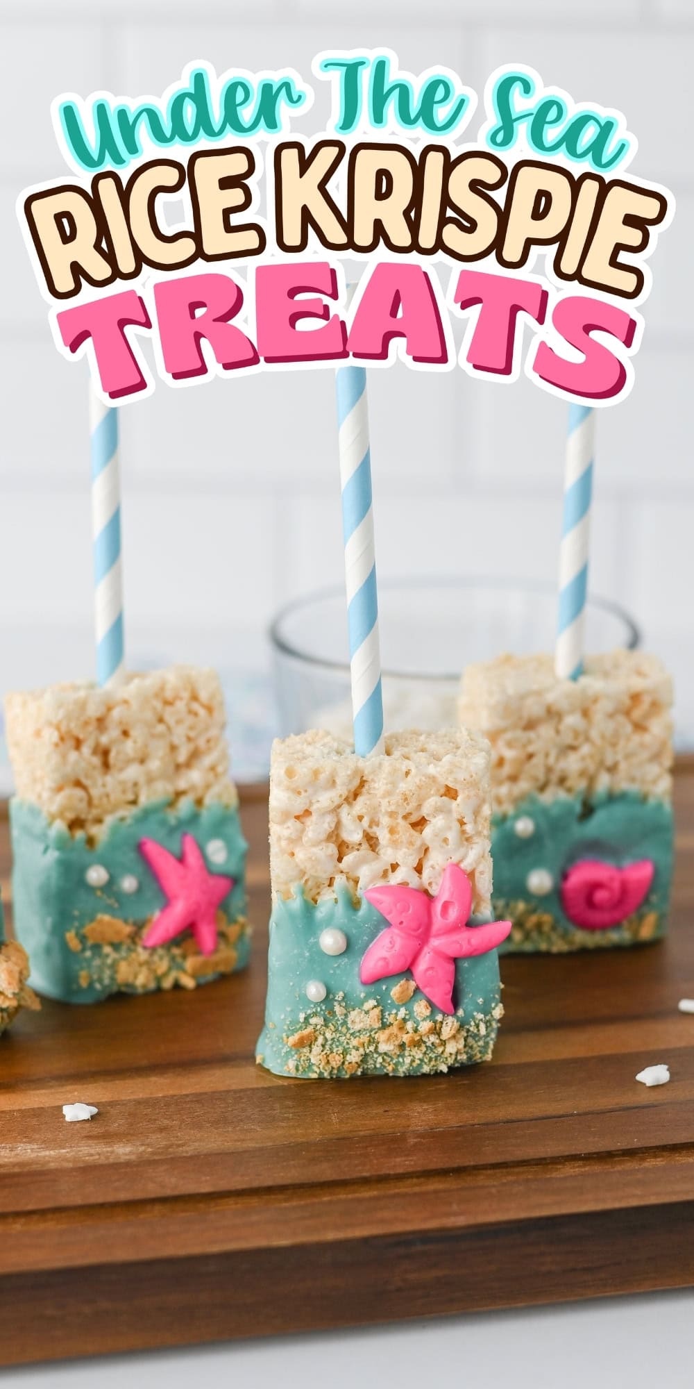 Three rice krispie treats on sticks, decorated with blue icing and sea-themed shapes.