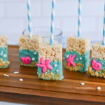 Rice Krispies treats on sticks, decorated with blue icing and pink sea creatures.