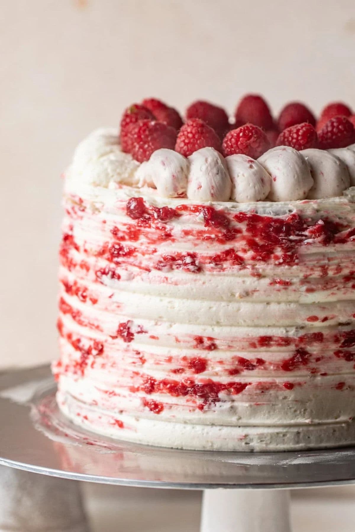 A layered cake with white frosting, raspberry swirls—classic for raspberry recipes.