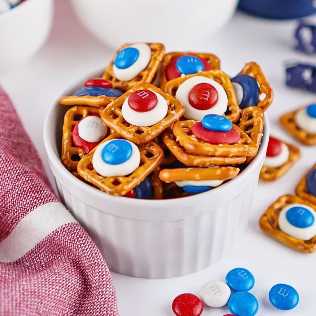 A bowl of pretzel snacks topped with red, white, and blue M&M candies.