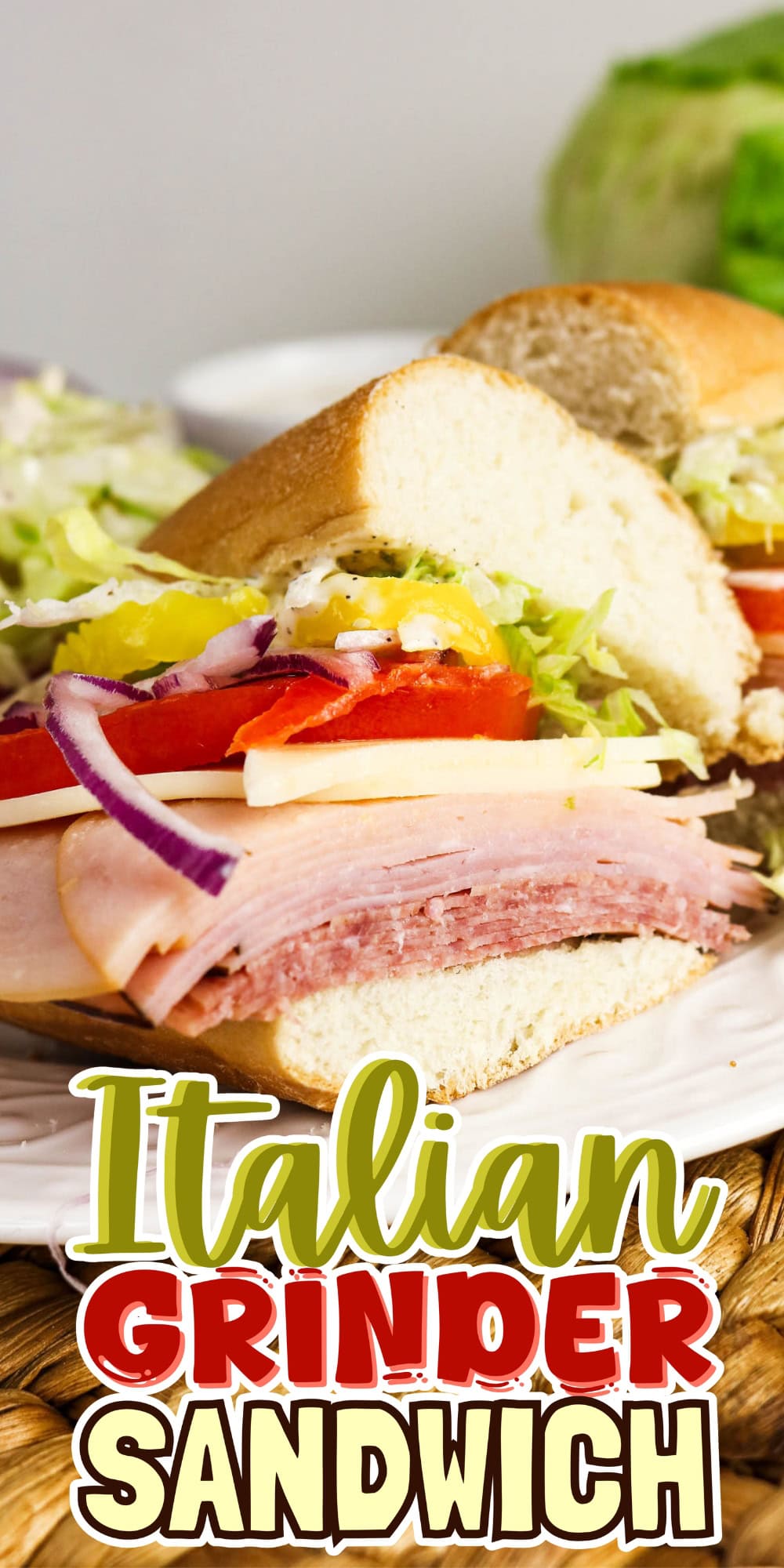 Italian grinder sandwich with meats, cheese, lettuce, tomato, and onion on a plate.