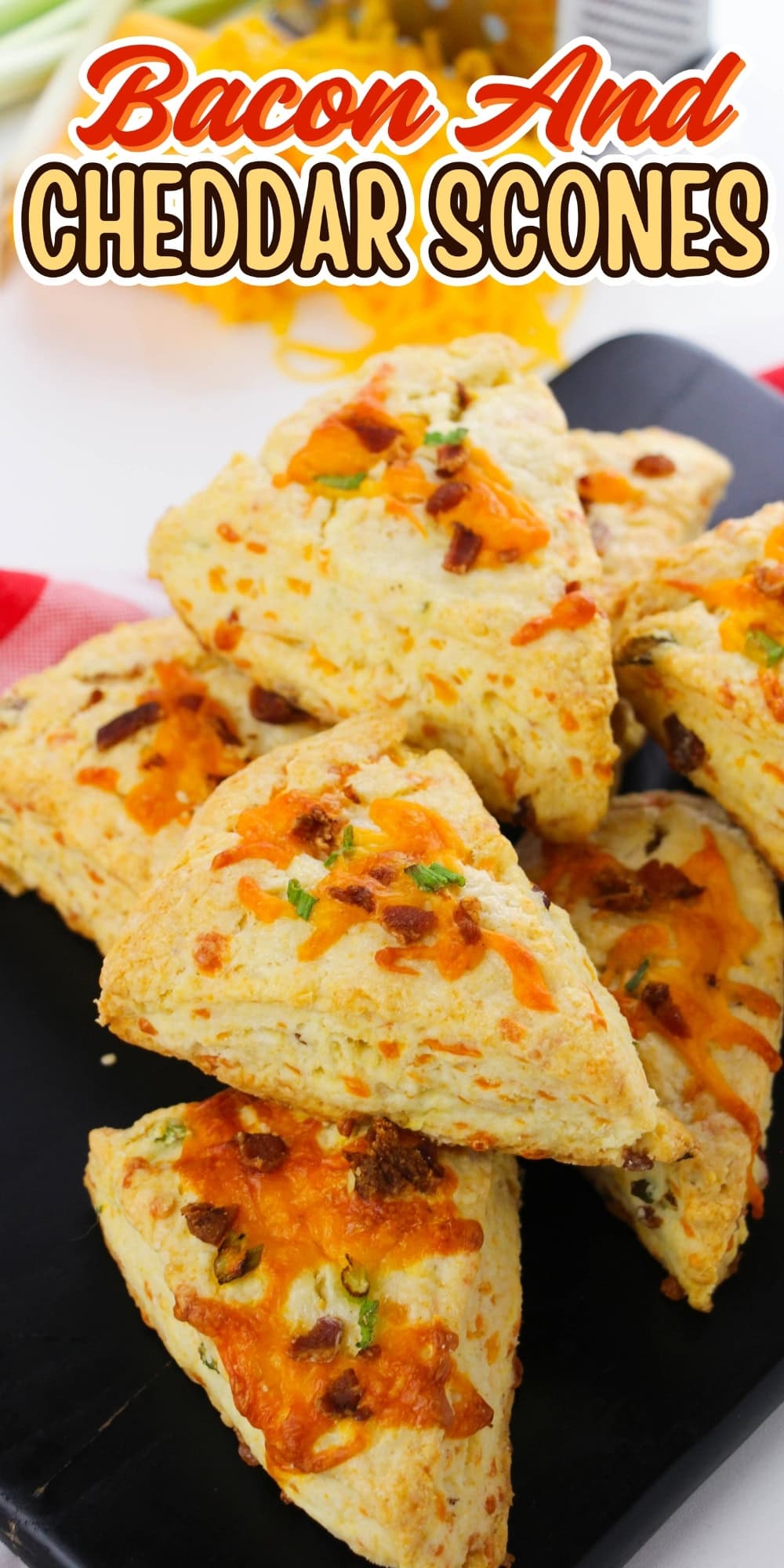 Bacon and cheddar scones stacked on a black tray with cheese and bacon topping.