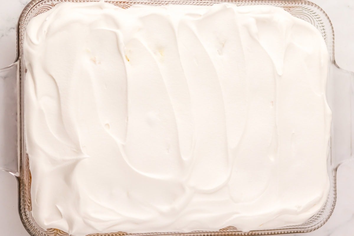 A glass dish filled with a dessert topped with smooth, white whipped cream.