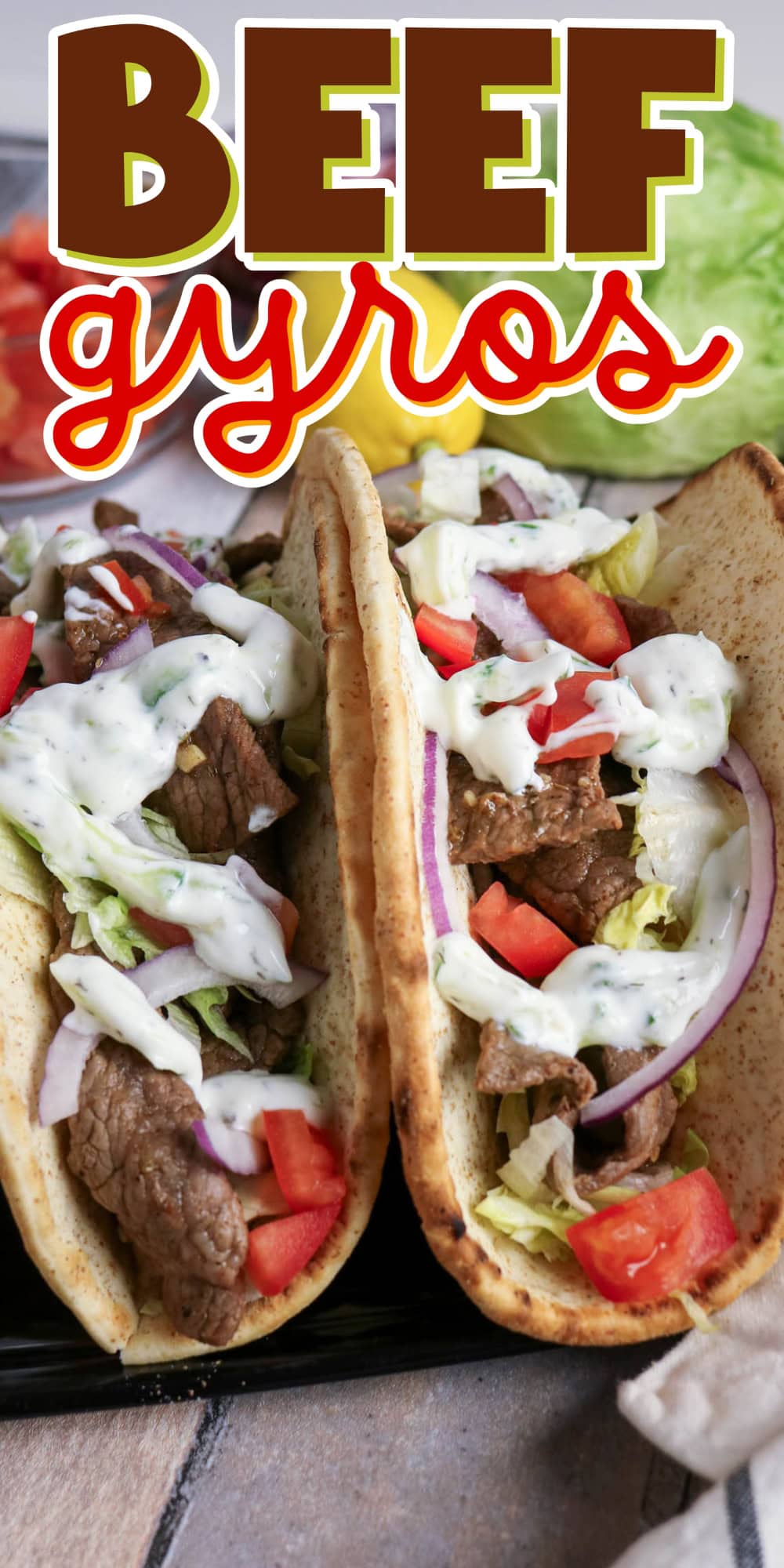 Two beef gyros with lettuce, tomato, onion, and tzatziki sauce in pita bread.