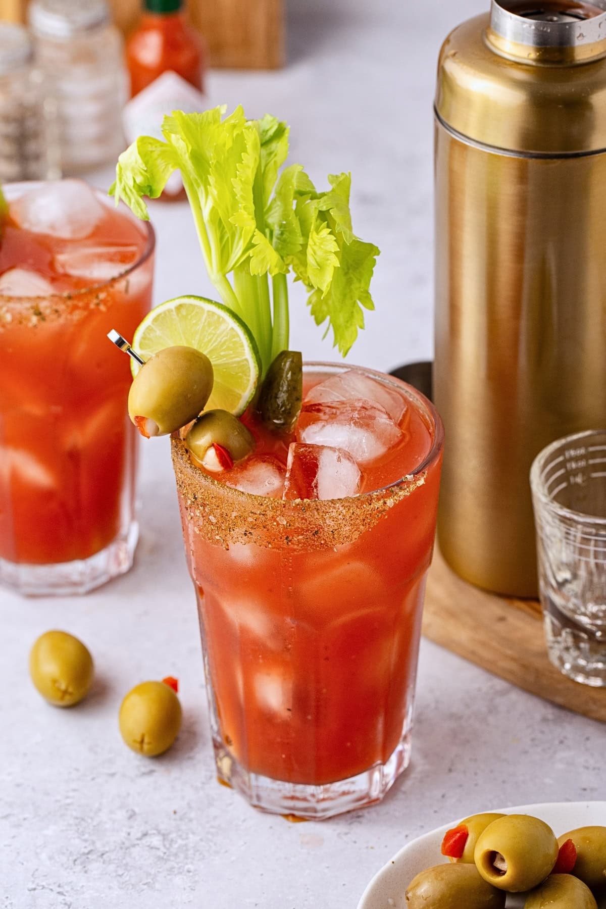 A Bloody Mary cocktail garnished with celery, olives, lime, and a jalape&ntilde;o.
