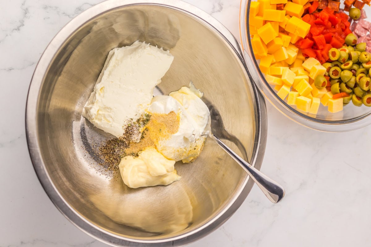 Metal bowl with cream cheese, mayo, seasoning; another bowl with chopped ingredients.