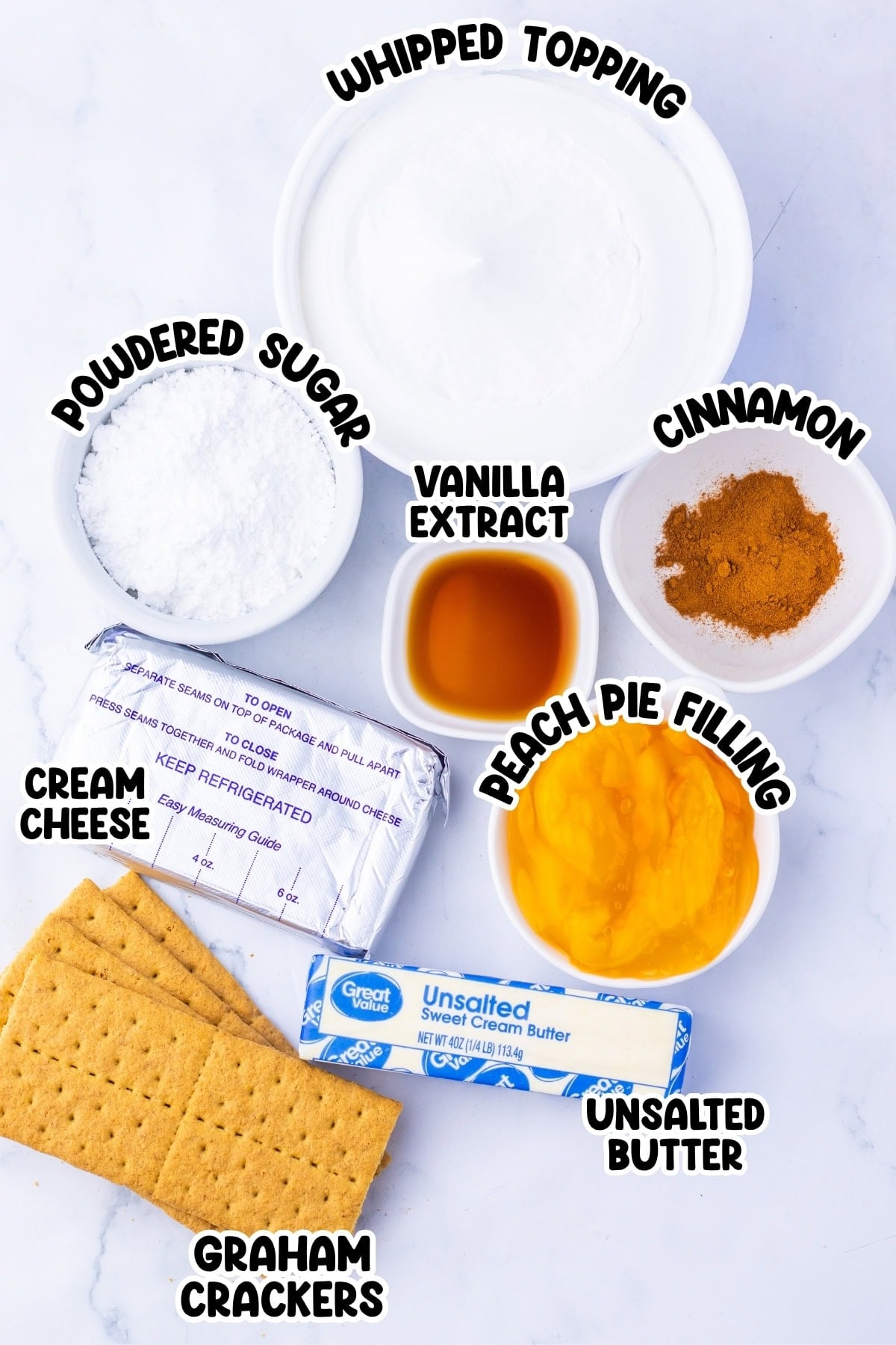 Bowls of whipped topping, powdered sugar, vanilla, cinnamon, cream cheese, peach pie filling, and graham crackers.
